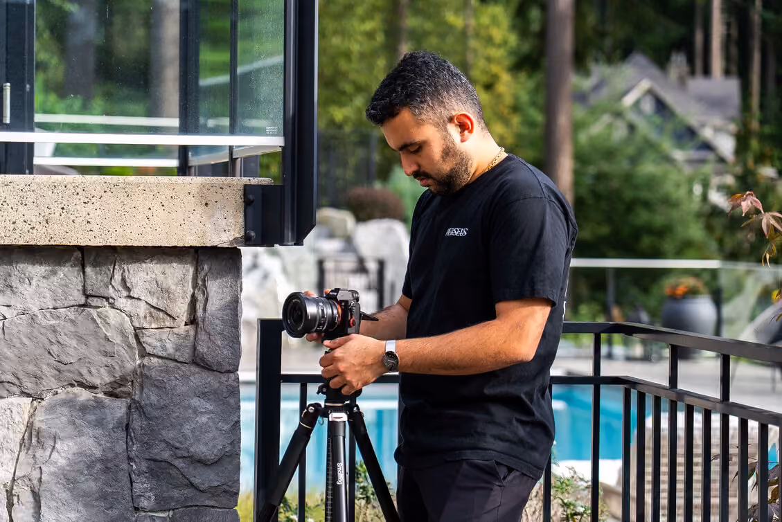 Perseus Creative Studio photographer setting up a tripod-mounted camera to shoot the exterior of a modern Vancouver home.